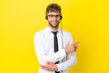 Sarı arka planda izole edilmiş kulaklığı olan, sarışın bir adam tele-pazarlamacı.
