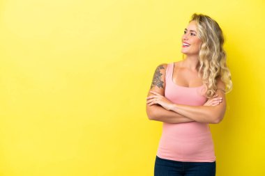 Sarı arka planda izole edilmiş genç Brezilyalı kadın mutlu ve gülümsüyor.