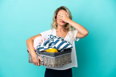 Elinde çamaşır sepeti tutan genç Brezilyalı bir kadın mavi arka planda tek başına gözlerini kapatıyor. Bir şey görmek istemiyorum.