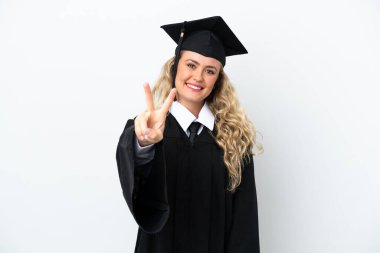 Üniversiteden mezun genç bir kadın beyaz arka planda izole edilmiş gülümsüyor ve zafer işareti gösteriyor.