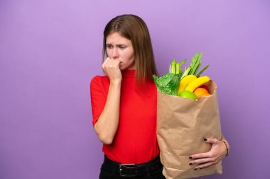 Mor arka planda izole edilmiş alışveriş torbası tutan genç bir İngiliz kadın şüpheleri var.