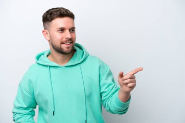 Beyaz arka planda izole edilmiş beyaz tenli genç adam parmağını yana doğru uzattı ve bir ürün sundu.