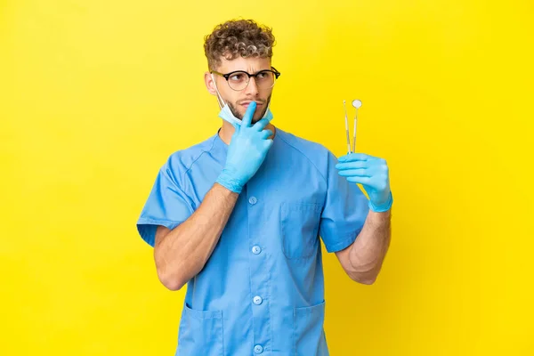 Dentista Loira Homem Segurando Ferramentas Isoladas Fundo Com Dúvidas Olhar — Fotografia de Stock