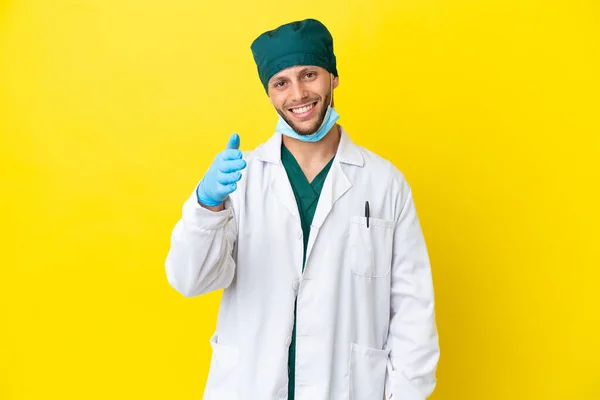 Χειρούργος Ξανθός Άνδρας Πράσινη Στολή Απομονωμένος Κίτρινο Φόντο Σφίγγει Χέρι — Φωτογραφία Αρχείου