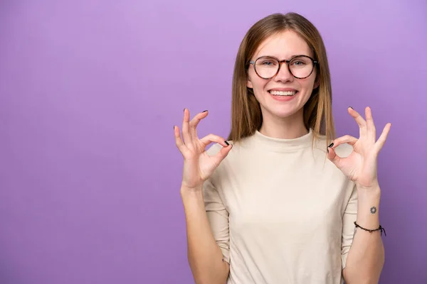 若いです英語の女性は紫の背景に隔離されました二つの手でOkサイン — ストック写真