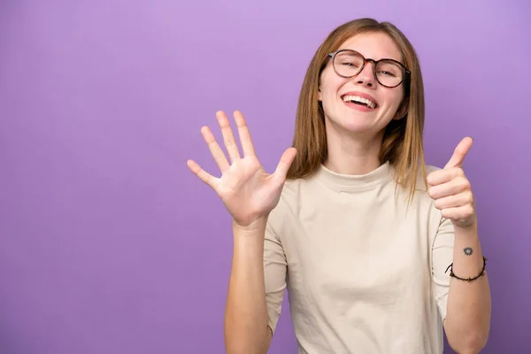 指で6を数える紫色の背景に隔離された若い英語の女性 — ストック写真