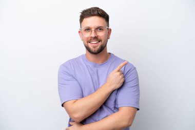 Beyaz arka planda izole edilmiş genç beyaz bir adam bir ürün sunmak için kenarı işaret ediyor.