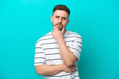 Kafkasyalı genç adam mavi arka planda soyutlanmış düşünüyor.