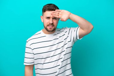 Kafkasyalı genç adam mavi arka planda izole edilmiş, yorgun ve hasta bir ifadeyle.