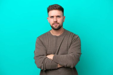 Mutsuz bir ifadeyle mavi arka planda izole edilmiş genç beyaz bir adam.