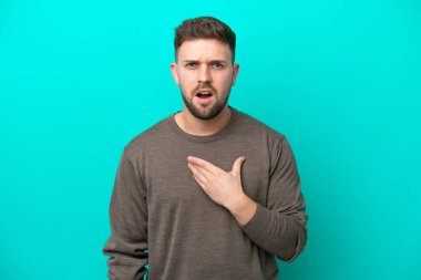 Mavi arka planda izole edilmiş genç beyaz adam kendini işaret ediyor.