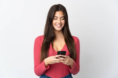 Genç Brezilyalı kız beyaz arka planda izole edilmiş bir şekilde cep telefonuyla mesaj ya da e-posta gönderiyor