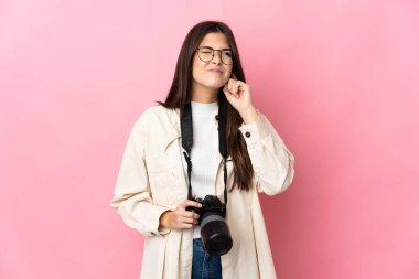 Genç fotoğrafçı Brezilyalı kız pembe arka planda izole edilmiş hayal kırıklığına uğramış ve kulaklarını kapatmış.