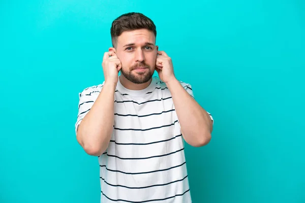 Jovem Caucasiano Isolado Fundo Azul Frustrado Cobrindo Orelhas — Fotografia de Stock