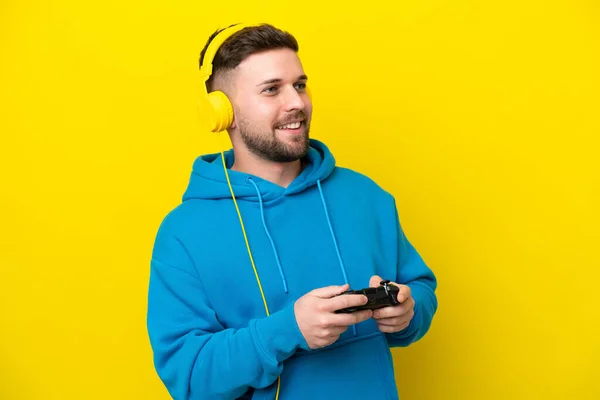 Jovem Caucasiano Jogando Com Controlador Videogame Isolado Fundo Amarelo Olhando — Fotografia de Stock