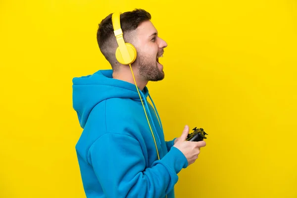 Jovem Caucasiano Jogando Com Controlador Videogame Isolado Fundo Amarelo Rindo — Fotografia de Stock