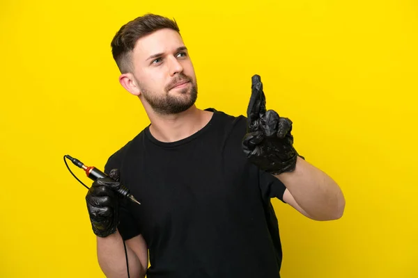 Tattoo Artist Man Isolated Yellow Background Fingers Crossing Wishing Best — Stock Photo, Image