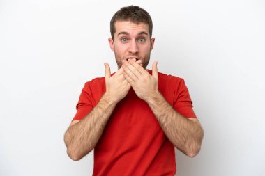 Beyaz arka planda izole edilmiş genç beyaz bir adam elleriyle ağzını kapatıyor.