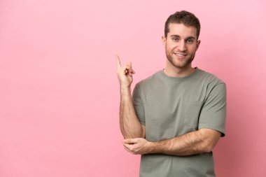 Pembe arka planda izole edilmiş genç beyaz adam mutlu ve yukarıya bakıyor.