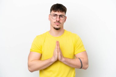 Beyaz arka planda izole edilmiş beyaz, yakışıklı genç bir adam avuç içlerini bir arada tutuyor. İnsan bir şey ister.
