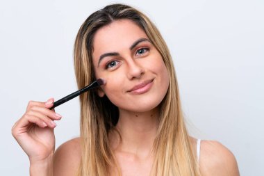 Beyaz arka planda izole edilmiş beyaz bir kadın elinde makyaj fırçası tutuyor.