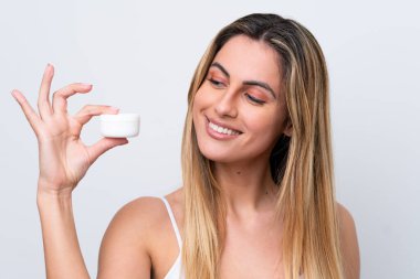 Beyaz arka planda nemlendirici ile izole edilmiş genç beyaz kadın.