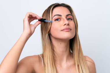 Beyaz arka planda izole edilmiş beyaz bir kadın elinde bir serum tutuyor. Portreyi kapat