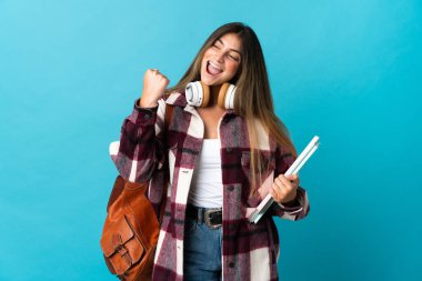 Mavi arka planda izole genç bayan bir zafer kutlaması yapıyor.