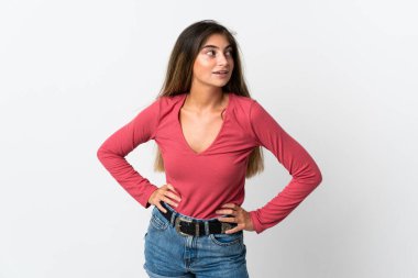 Beyaz arka planda izole edilmiş genç beyaz kadın kolları kalçasında ve gülümsüyor.