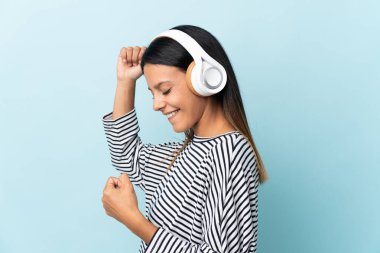 Beyaz kız mavi arka planda izole edilmiş müzik ve dans dinliyor.