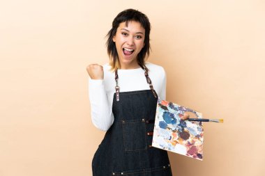 Arkaplanda palet tutan genç bir sanatçı zaferi kutluyor.