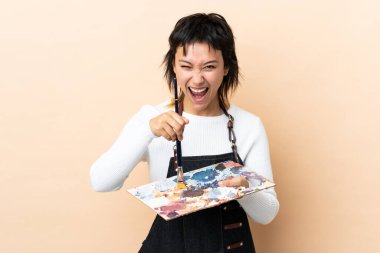 Soyutlanmış arka planda palet tutan genç sanatçı.