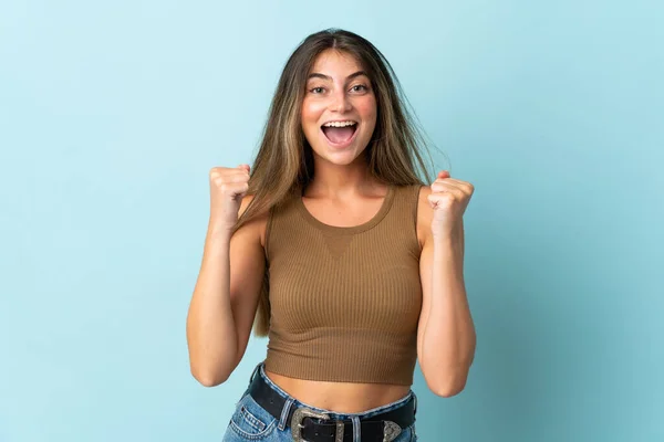Mavi Arka Planda Izole Edilmiş Genç Beyaz Kadın Galibiyeti Kutluyor — Stok fotoğraf