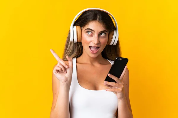 Νεαρή Καυκάσια Γυναίκα Απομονωμένη Κίτρινο Φόντο Ακούγοντας Μουσική Κινητό Και — Φωτογραφία Αρχείου