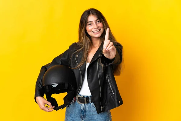 黄色の背景を示すと指を持ち上げる上で単離されたオートバイのヘルメットを保持女性 — ストック写真