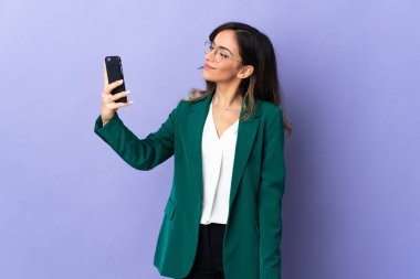 Mor arka planda izole edilmiş beyaz bir kadın selfie çekiyor.