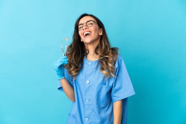 Mavi arka planda aletleri tutan kadın gülüyor.