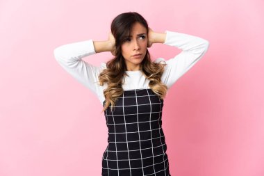 Pembe arka planda izole edilmiş genç beyaz kadın hayal kırıklığına uğramış ve kulaklarını kapatmış.