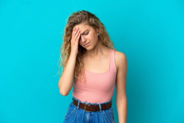 Mavi arka planda başağrısı olan genç sarışın kadın.