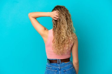 Genç sarışın kadın mavi arka planda izole edilmiş ve düşünüyor.