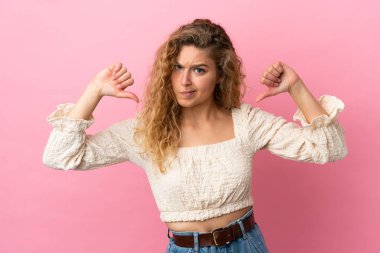 Genç sarışın kadın pembe arka planda soyutlanmış gururlu ve kendinden memnun