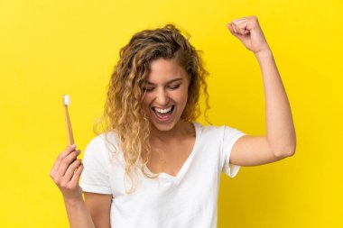 Sarı arka planda dişlerini fırçalayan beyaz bir kadın zaferi kutluyor.