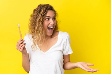 Sarı arka planda dişlerini fırçalayan beyaz bir kadın sürpriz bir ifadeyle yan yana bakarken...