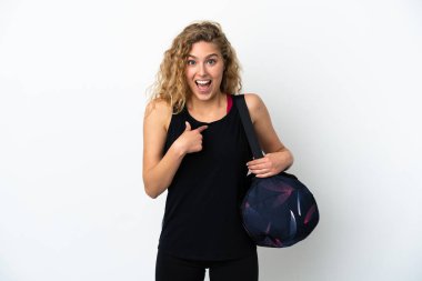 Spor çantalı genç bir kadın beyaz arka planda, şaşırmış bir yüz ifadesi var.