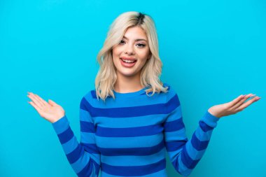 Genç Rus kadın mavi arka planda izole edilmiş, şok olmuş yüz ifadesi var.