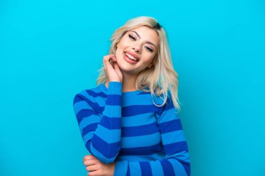 Genç Rus kadın mavi arka planda yalnız gülüyor.