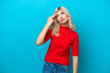 Genç Rus kadın, mavi arka planda izole edilmiş ve intihar jestinde sorun yaşıyor.