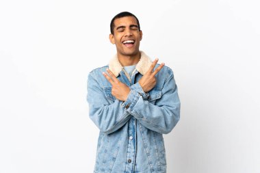 İzole edilmiş beyaz arka plan üzerinde gülümseyen ve zafer işareti gösteren Afrikalı Amerikalı bir adam.