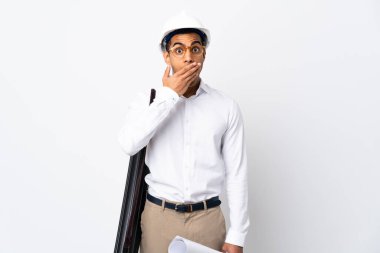 Miğferli Afrikalı Amerikalı mimar izole edilmiş beyaz arka plan üzerinde planlar tutuyor. Mutlu ve gülümsüyor. Ağzını eliyle kapatıyor.