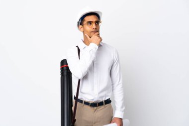 Miğferli ve elinde izole edilmiş beyaz arkaplan üzerine planlar tutan Afro-Amerikalı mimar şüpheleri ve kafa karıştırıcı yüz ifadesiyle